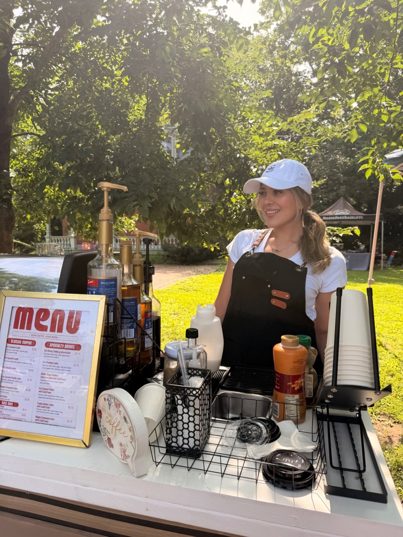 Serving drinks from the Ya Hala Coffee cart under the trees